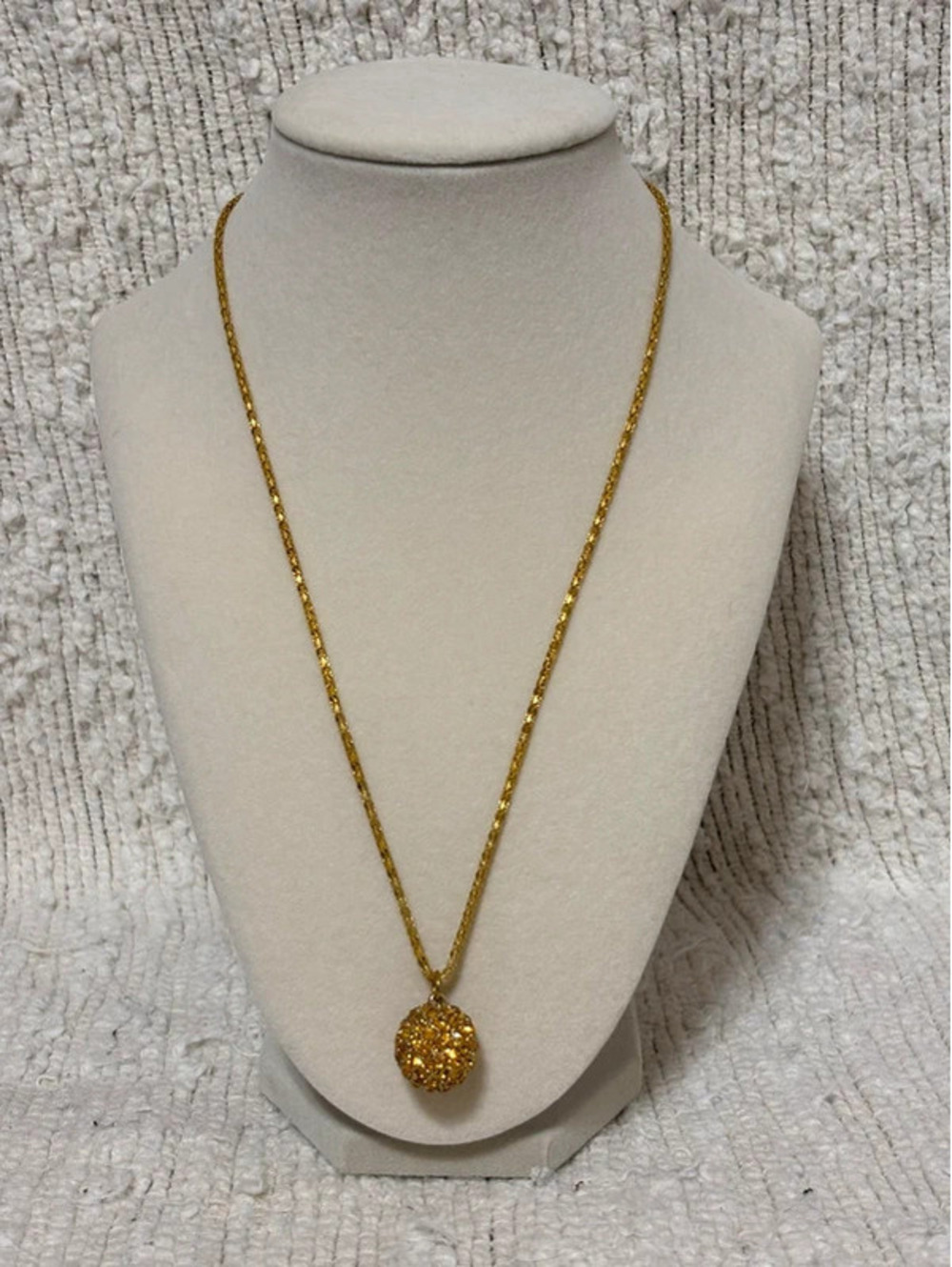 Gold-tone chain necklace with a spherical rhinestone ball pendant